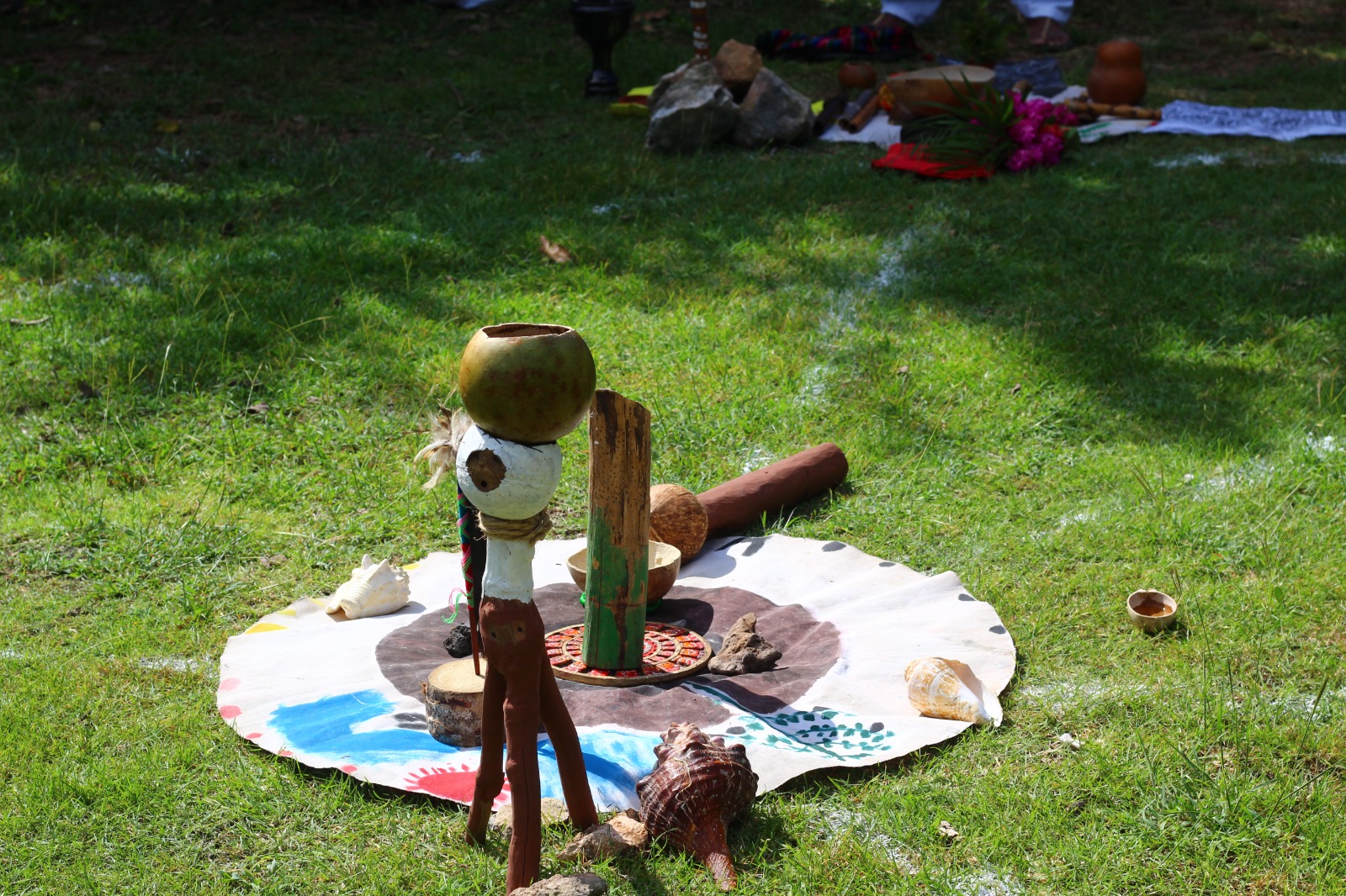 Altar ceremonial con objetos tradicionales colocados sobre un lienzo circular en el pasto
